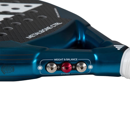 Close-up of the adidas Metalbone CTRL 3.3 Padel Racket’s bridge, highlighting its “Weight & Balance System” with two adjustable screws and a red center knob. The textured surface and part of the white handle are also visible.