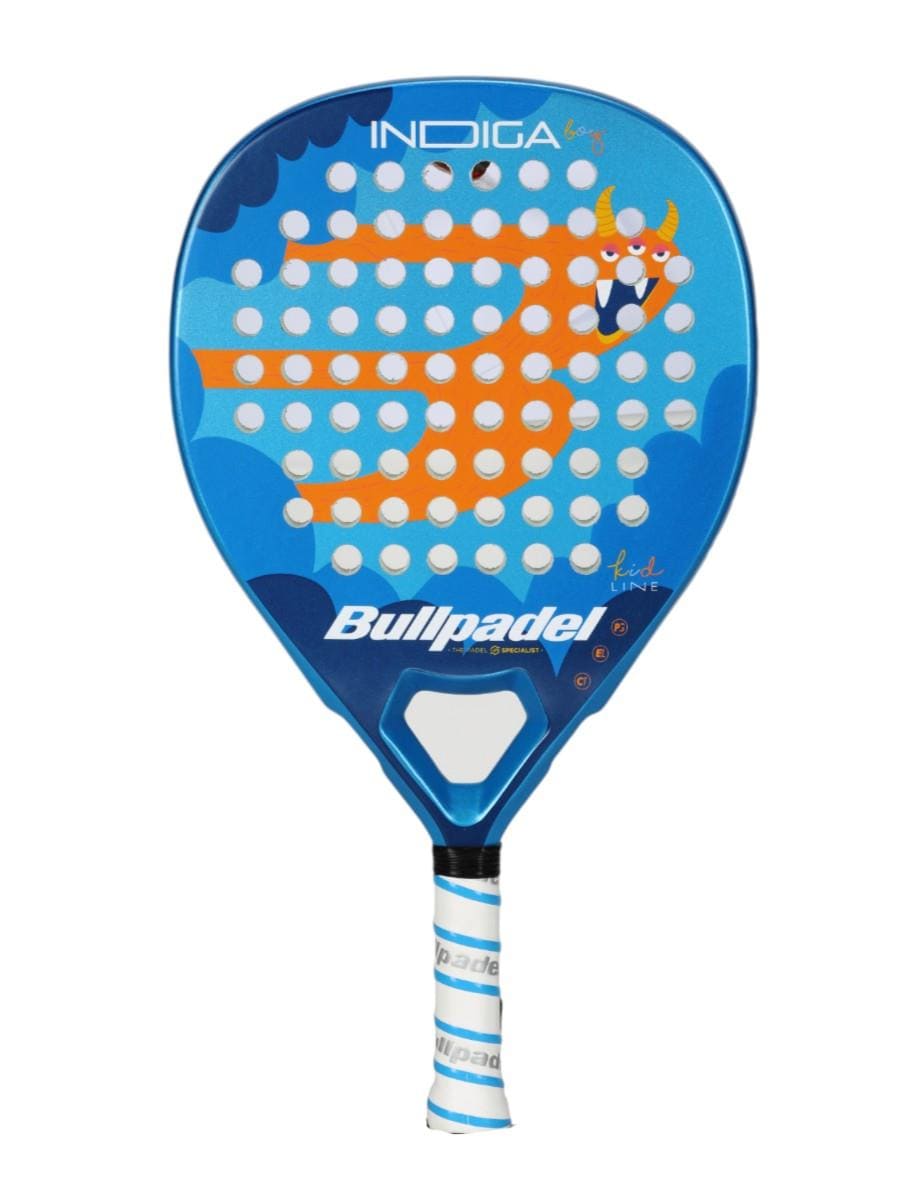 The Bullpadel Indiga Junior 25 Boys Padel Racket features a blue design with white holes, an orange cartoon monster with a smile, big eyes, and three horns on the front, plus a white and blue grip. Brand: Bullpadel.
