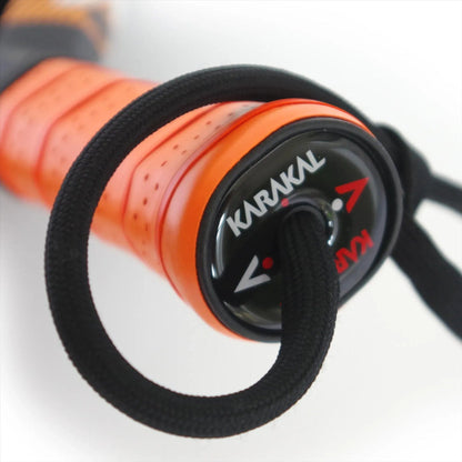 Close-up of the lightweight Karakal Air Lite 345 Orange Padel Racket handle, labeled "Karakal," featuring a black cord at the end. The brand logo and directional arrows appear on the handle cap.