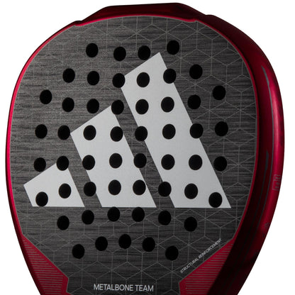Close-up of the adidas Metalbone Team 3.3 padel racket in black, featuring a bold white geometric logo, circular holes, "Metalbone Team" text on the base, and advanced Spin Blade Grit technology for enhanced control.