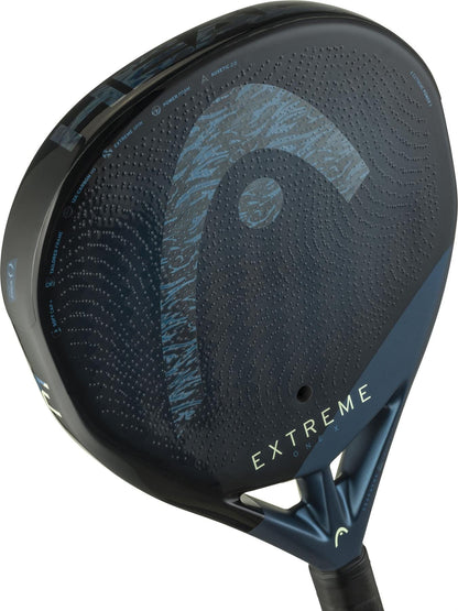 A close-up of the HEAD Extreme One X 2025 Padel Racket highlights its dark blue and black design, bold "EXTREME" branding, a striking HEAD logo, and a textured 12K Carbon Fibre surface perforated with small holes.