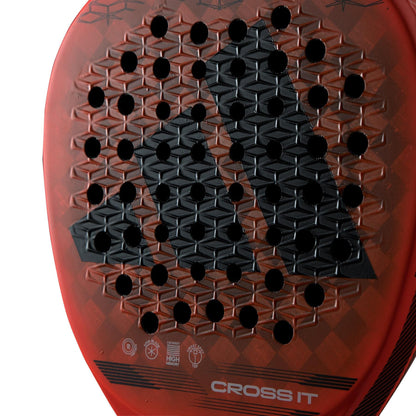 Close-up of the adidas Cross It Padel Racket, a professional racket featuring a honeycomb pattern, ventilation holes, and "CROSS IT" at the bottom. Designed for power and spin with a bold black geometric logo in the center.