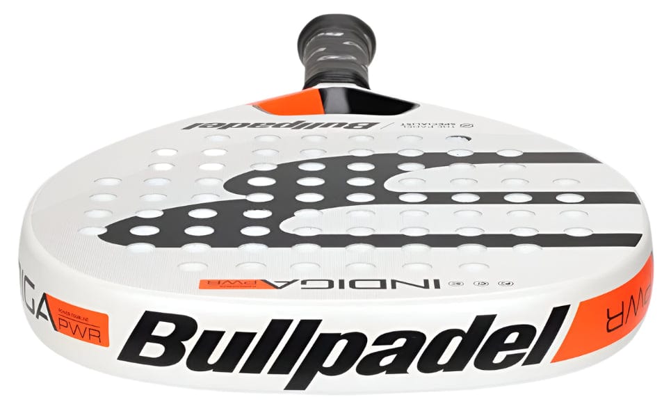 A detailed look at the Bullpadel Indiga Pwr 2025 padel racket, mainly white with black and orange details, displays "Bullpadel" on the side and a perforated surface built for powerful performance.