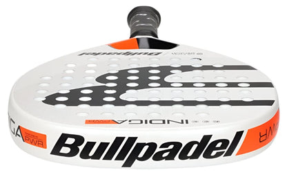 A detailed look at the Bullpadel Indiga Pwr 2025 padel racket, mainly white with black and orange details, displays "Bullpadel" on the side and a perforated surface built for powerful performance.