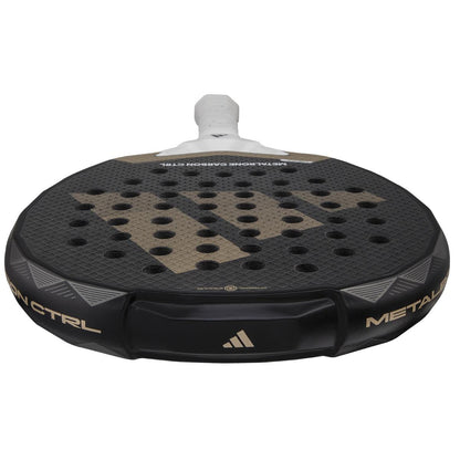 The adidas Metalbone Carbon CTRL 3.4 padel racket features a black design with gold accents, a textured round surface, multiple circular holes, "METALBONE" on the rim, and a white grip tape handle—ideal for advanced players.