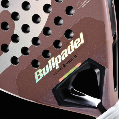 Close-up of the Bullpadel Wonder 2026 Padel Racket, showing the iridescent Bullpadel logo, a Hyper Core textured surface with holes, geometric design elements, a hint of tricolor detail, and part of the grip area.