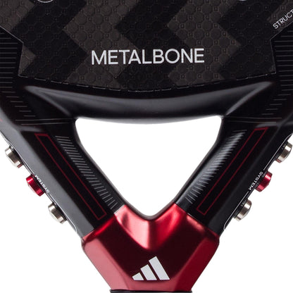 Close-up of the lower section of the adidas Metalbone 3.3 Padel Racket, featuring "METALBONE" on the face, the adidas logo near the handle, and a textured, carbon fiber-like surface.
