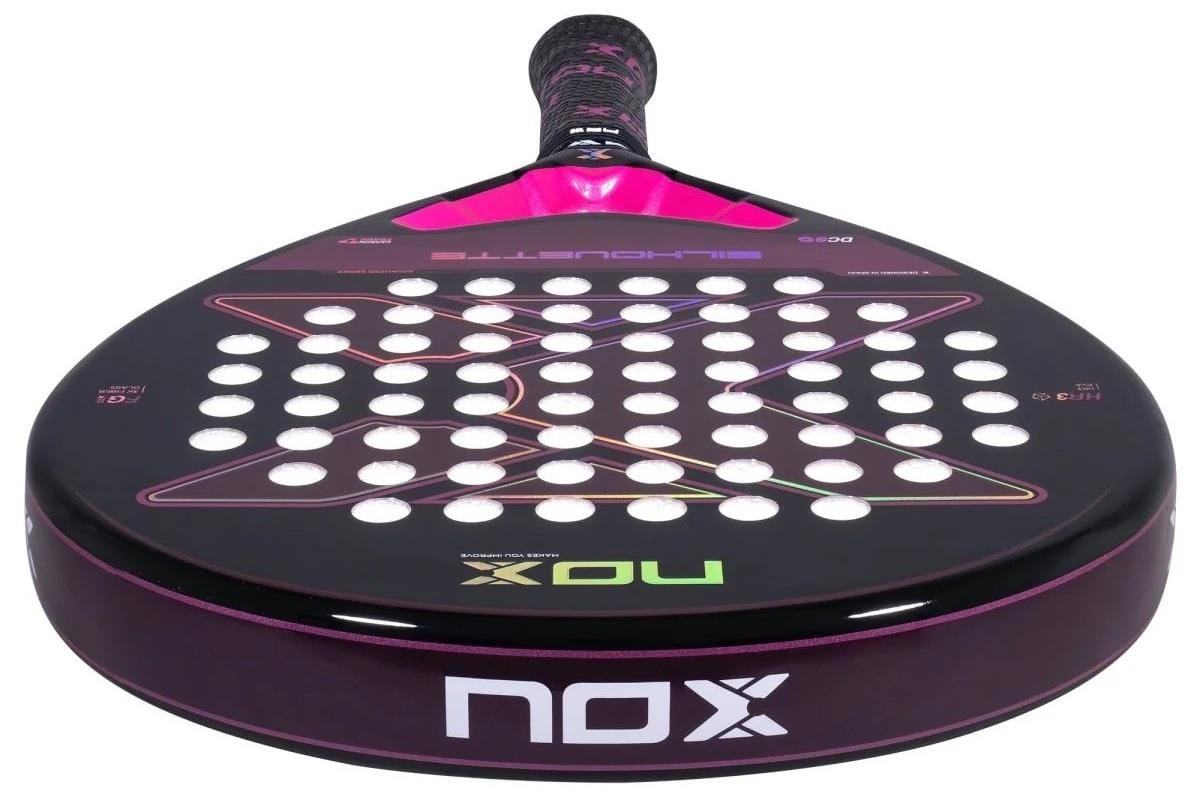 A close-up of the NOX X-One Silhouette Advance Series Padel Racket, featuring a black and pink design with white holes and the "NOX" logo—perfect for beginner and intermediate players.