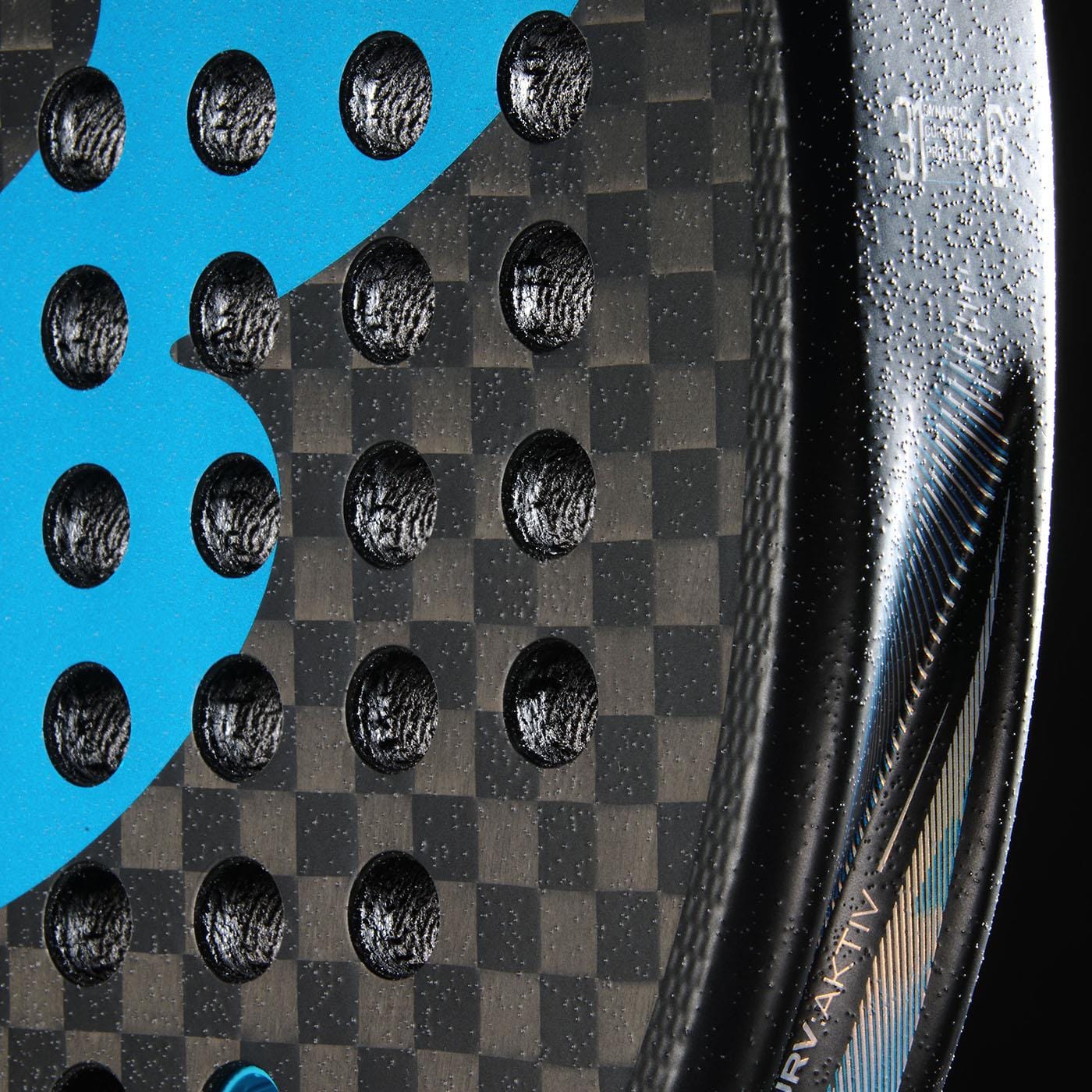 Close-up of the Bullpadel Vertex 05 Hybrid 2026 Padel Racket by Bullpadel, featuring a carbon fiber texture, hybrid shape, perforated holes, blue graphics, metallic accents, and small white text along the edge.