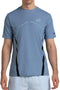 A man wears a Bullpadel Cabore Men's Padel T-Shirt in shadow blue by Bullpadel with white athletic shorts, standing against a plain white background. His face is not visible.