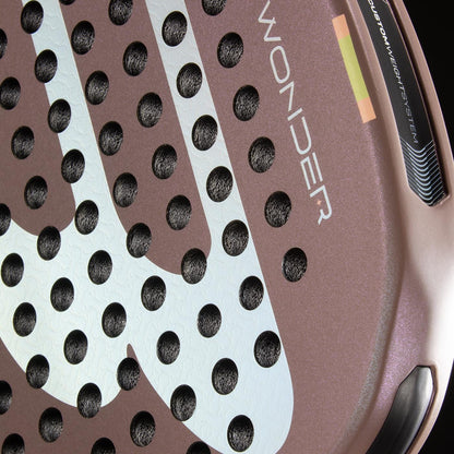 Close-up of the Bullpadel Wonder 2026 Padel Racket by Bullpadel, showcasing its textured surface with circular holes and "WONDER" printed on it. This professional racket features brown and white tones with black and yellow Hyper Core accents.