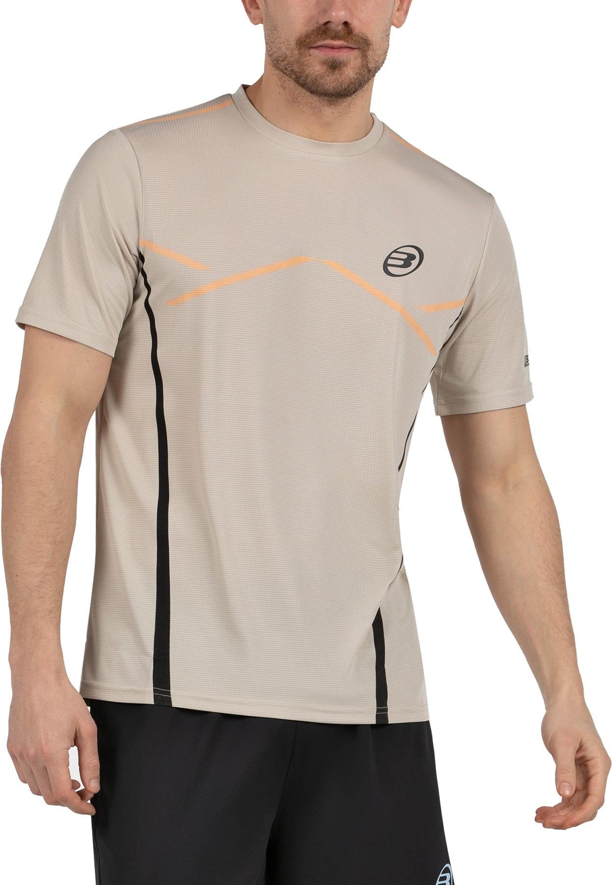 A man wears a Bullpadel Cabore Mens Padel T-Shirt in Peanut and black shorts, with subtle orange and black Court Line accents, standing against a plain background. His head is partially out of frame.