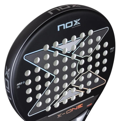 Close-up of the NOX X-One Advance Series Padel Racket in black, featuring a large X design, multiple circular holes, visible NOX branding, and an HR3 rubber core for enhanced performance.
