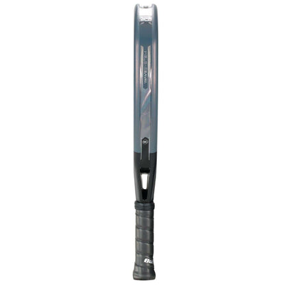 The Bullpadel XPLO Comfort 2026 Padel Racket, shown from the side, features a thin frame, black grip handle, dark gray color with blue accents, and a prominent Bullpadel logo for exceptional comfort.