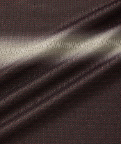 Close-up of the Yonex 10711YX Crew Neck Mens Padel T-Shirt in black, showing its dark brown textured fabric with small red dots and a zigzag seam. Light reflections highlight the surface and texture of this Yonex performance sportswear.