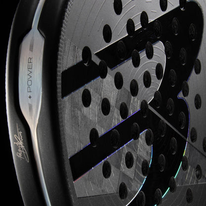 Close-up of the Bullpadel HACK 04 Hybrid 2026 Padel Racket, featuring round holes, a prominent “S” logo, a signed edge with “POWER” in metallic, and Total Channel technology by Bullpadel for top performance.
