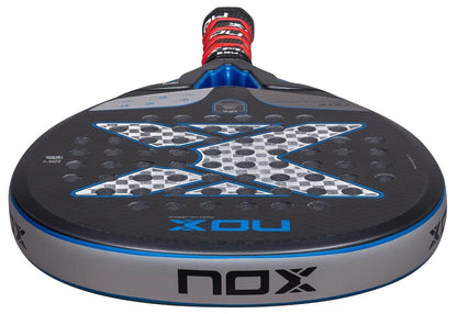 Close-up of the NOX NFA Future Hybrid 12K Alum Padel Racket by NOX, showcasing its textured black carbon surface, striking silver and black "X" design, round hole pattern, and wrapped handle with a red and black grip.
