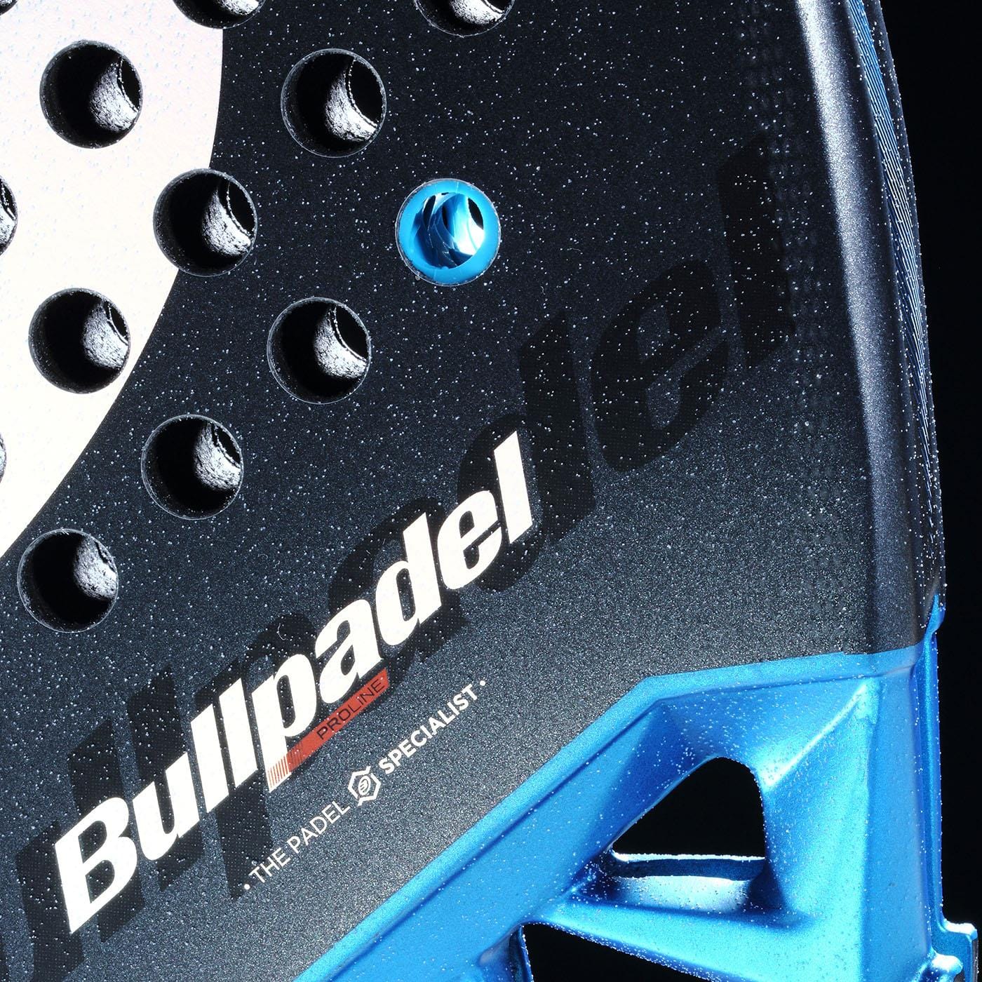 Close-up of a black and blue Bullpadel Vertex 05 Comfort 2026 padel racket with "THE PADEL SPECIALIST" printed on its Fibrix fibre textured surface and the Bullpadel brand name.