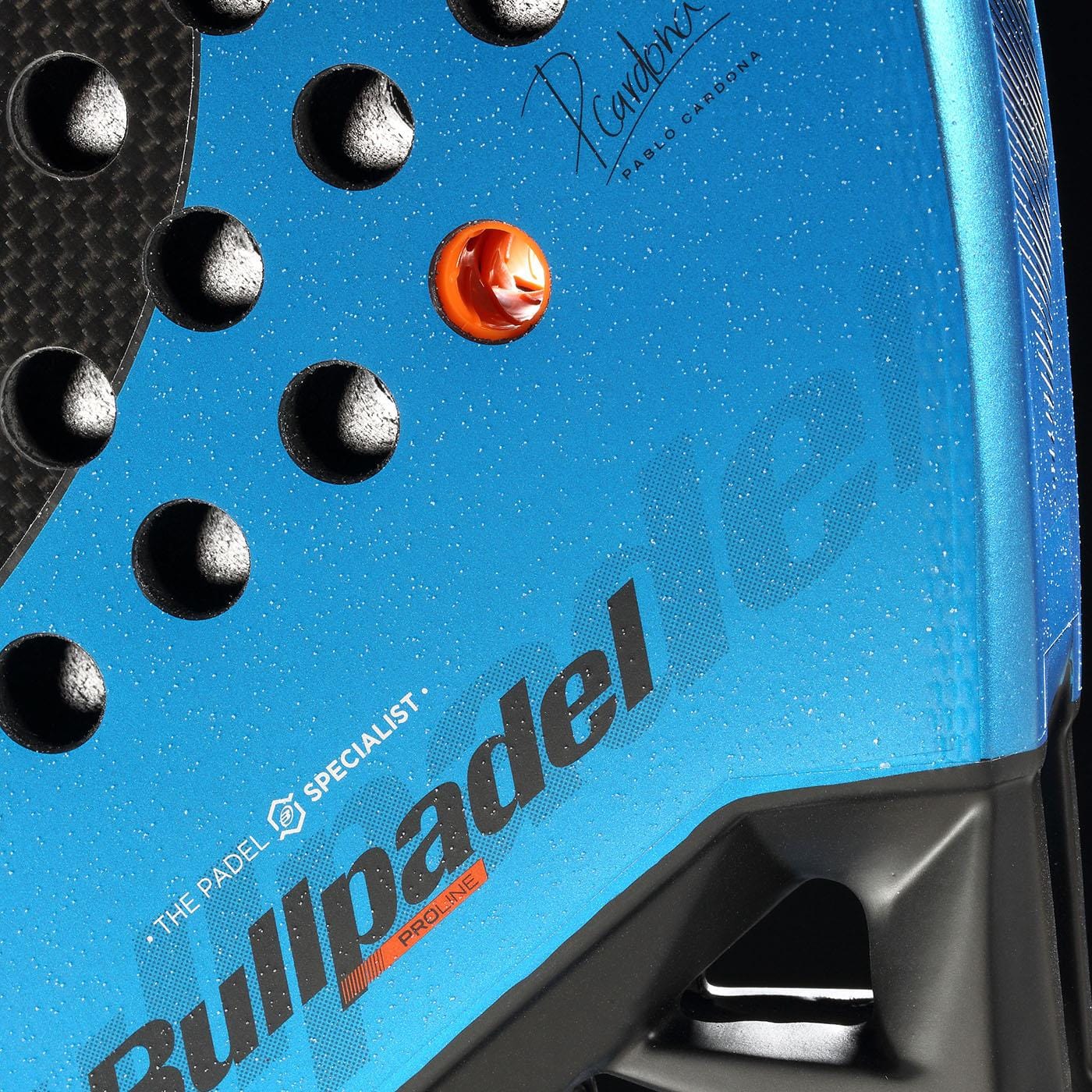 Close-up of the Bullpadel Vertex 05 GEO 2026 Padel Racket in blue, with textured black dots, an orange button, and "Bullpadel" branding plus a signature in the upper right corner.