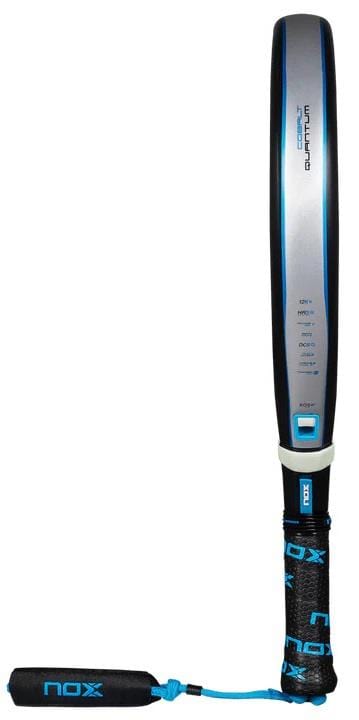 The NOX Luxury Quantum 12K Cobalt 2025 Padel Racket features a black and blue handle, gray face with blue accents, black grip with blue “nox” branding, 12K carbon fiber construction, and a matching wrist strap.