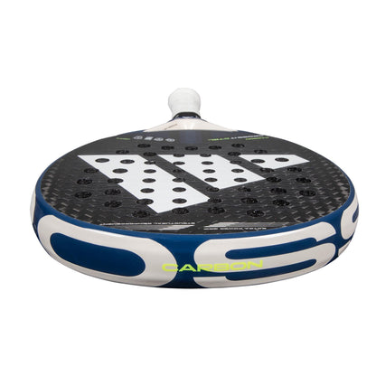 The adidas Cross It Carbon CTRL Padel Racket is a black carbon fibre racket with white and blue accents, a large white geometric logo, circular holes, and "CARBON" in yellow by the edge.