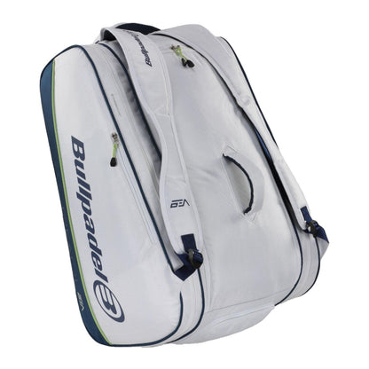The Bullpadel Pearl 25 Padel Racket Bag in white features "Bullpadel" branding, blue accents, multiple zippered compartments, a handle, and shoulder straps—perfect for fans of Bea González to carry sports gear.