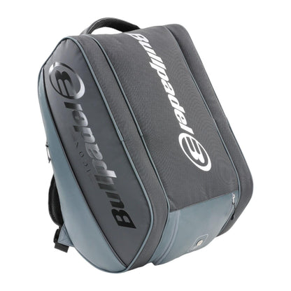 Introducing the Bullpadel Icon 25 Padel Racket Bag - Graffiti: a grey and black bag with a spacious compartment and padded straps. Featuring the Bullpadel logo in white, it's perfect for fans of legends like Juan Martín Díaz on the court.