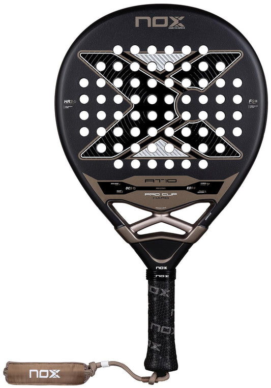 The NOX AT10 Pro Cup Hard By Agustín Tapia 2026 Padel Racket features a black and bronze design with a large "X", multiple perforations, a labeled handle with a black grip, and a NOX wrist strap. Inspired by Agustín Tapia.