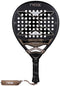 The NOX AT10 Pro Cup Hard By Agustín Tapia 2026 Padel Racket features a black and bronze design with a large "X", multiple perforations, a labeled handle with a black grip, and a NOX wrist strap. Inspired by Agustín Tapia.