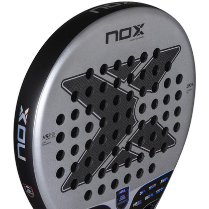 Close-up of the NOX NFA Nextgen Pro Hybrid 3K Padel Racket, featuring a black and silver design. The carbon 3K face shows a large "X" pattern, holes, NOX branding, logo, and technical specs.