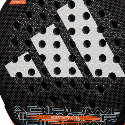 Close-up of the adidas ADIDAS Adipower CTRL 3.3 Padel Racket featuring a black textured surface, large white geometric logo, circular holes, and "ADIPOWER CTRL" in orange—an elite control padel racket by adidas.
