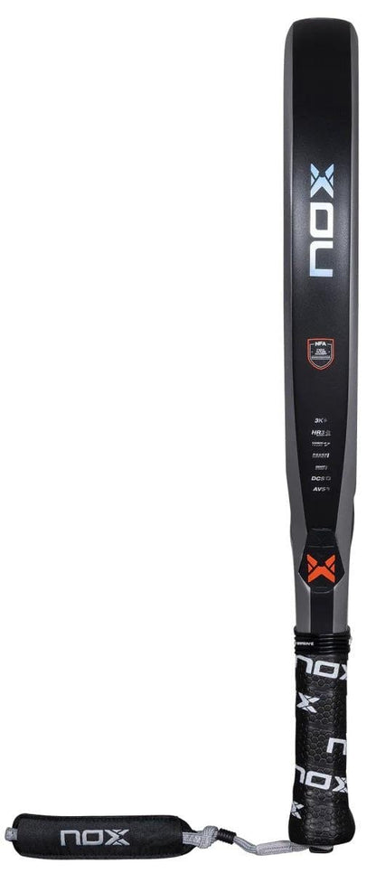 The NOX NFA Nextgen Pro Hybrid 3K Padel Racket is black with a white and orange logo, features a carbon 3K textured surface, and has a wrapped handle with NOX branding plus an attached wrist strap.