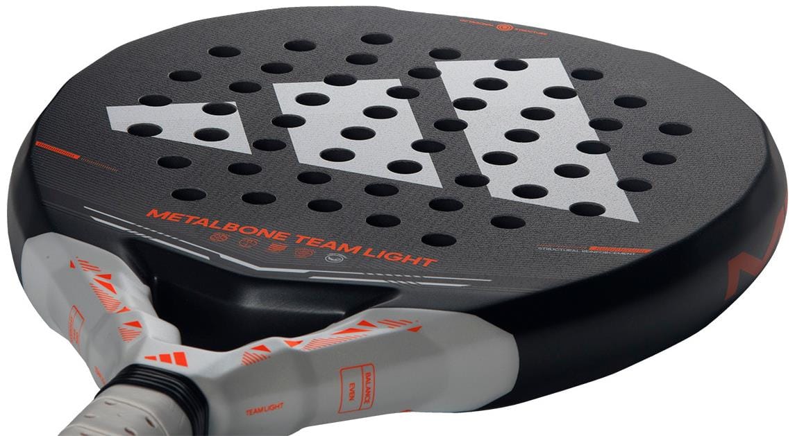 Close-up of the adidas Metalbone Team Light 2026 Padel Racket for advanced players, featuring a black surface with white and orange accents, geometric logo, “METALBONE TEAM LIGHT” text, and multiple round holes.