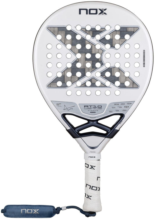The NOX AT10 Genius 12K Alum Extrem Lite By Agustín Tapia 2026 Padel Racket features a white/gray design with circular holes, black X graphic, NOX branding, Weight Balance system, white grip tape handle, and a safety strap.