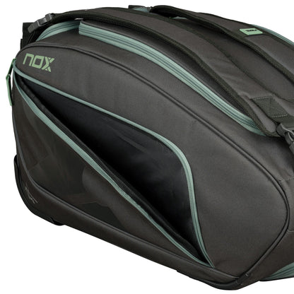 A close-up of the NOX AT10 Competition Trolley Padel Racket Bag - Black / Green by NOX, featuring green zippers and one partially open compartment. This wheeled padel bag offers smooth, durable fabric and a sturdy build.