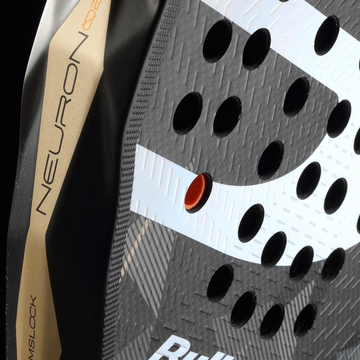 Close-up of the Bullpadel Neuron 02 2026 padel racket: circular holes, textured black and gold design, "NEURON" in gold on the edge, orange ring in one hole, and partial white "Bull" branding visible.