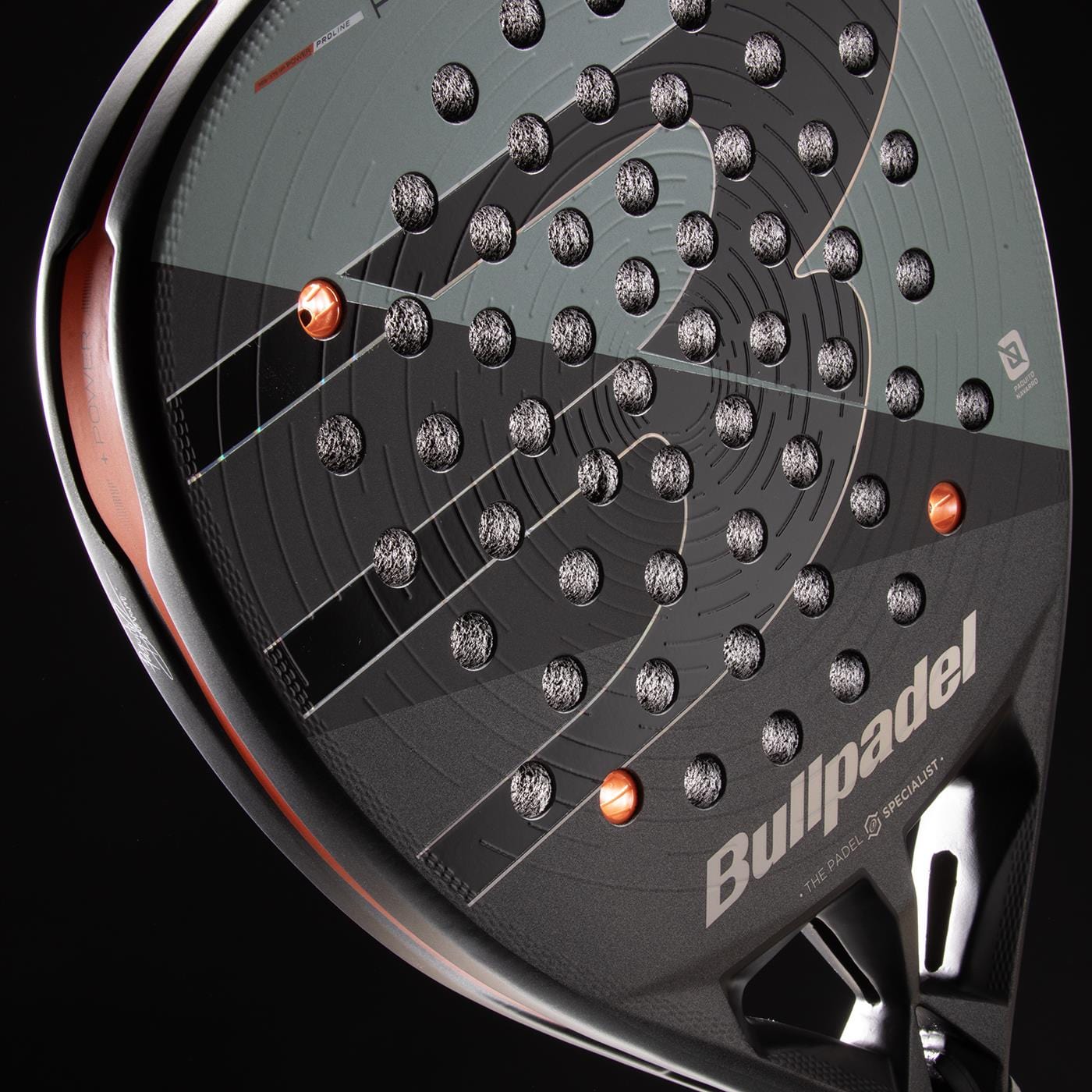 Close-up of the Bullpadel HACK 04 Comfort 2026 Padel Racket by Bullpadel, showing its black and gray design, Air React Channel system for power and control, multiple small holes, and silver-orange accents on a black background.