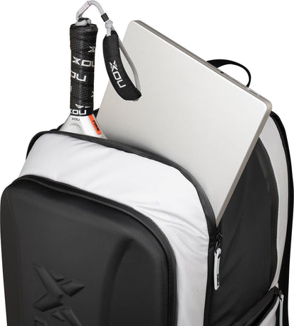 The NOX Luxury Master Series Padel Backpack - Black / White is shown unzipped, with a padel racket and a silver laptop partially visible inside the main compartment.