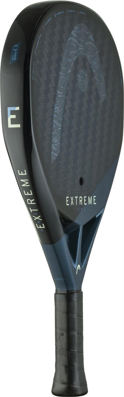 The HEAD Extreme One 2025 Padel Racket features a black and dark blue design with "HEAD" and "EXTREME ONE" on the face and throat, a 12K Carbon Fibre texture for Extreme Spin, and a wrapped handle.