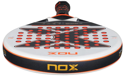A close-up of the NOX ML10 Luxury Quantum 3K By Miguel Lamperti 2025 Padel Racket shows its black, white, and orange colors, bold X design, red circular holes, and advanced NOX HR3 rubber for top performance.