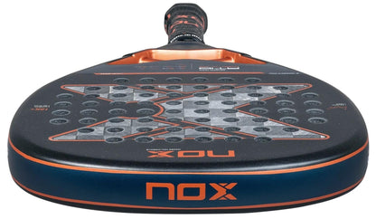 Close-up of the NOX AT10 Luxury Genius Attack 18K Alum By Agustin Tapia 2025 padel racket, featuring a striking black and orange design, perforated face, and the prominent NOX logo on the head.