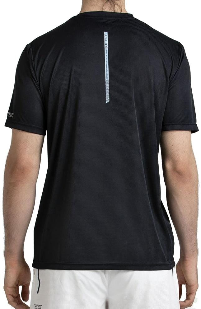 A person with long hair is shown from the back, wearing a Bullpadel Casinas Mens Padel T-Shirt in black and white shorts, against a plain white background.