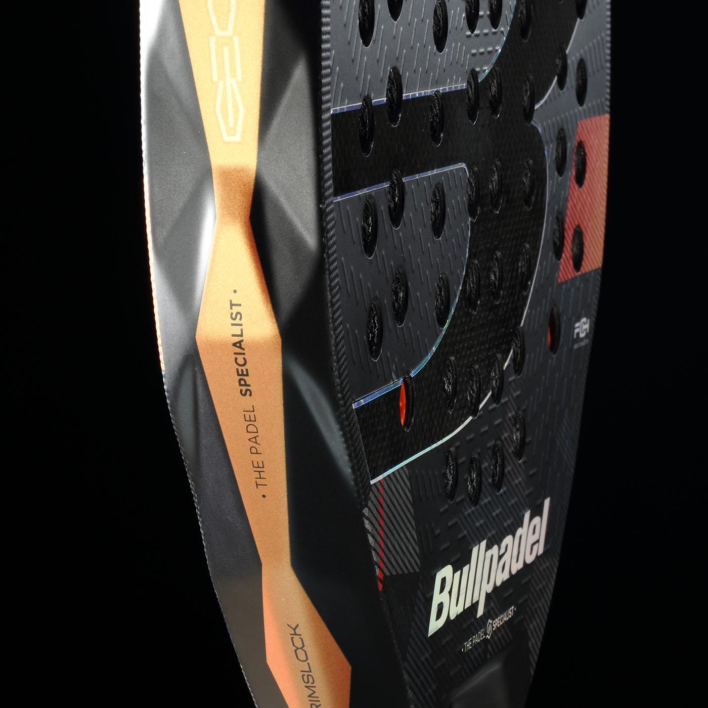 Close-up of the Bullpadel Neuron 02 Edge 2026 Padel Racket by Bullpadel, highlighting its textured black surface with small holes, orange and gold edge details, and branding text against a black background.