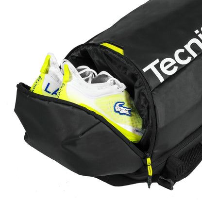The Tecnifibre Reform Padel Backpack - Black by Tecnifibre features a zippered compartment, partially open to reveal white and yellow athletic shoes inside, and is crafted from durable EVA material for lasting performance.