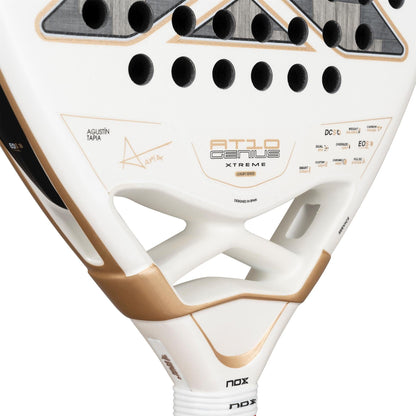 Close-up of the NOX AT10 Genius 12K Alum Extrem By Agustín Tapia 2026 Padel Racket, showing gold accents, geometric cutouts, "AT10 Genius" branding, technical specs, and Agustín Tapia’s name near the throat.