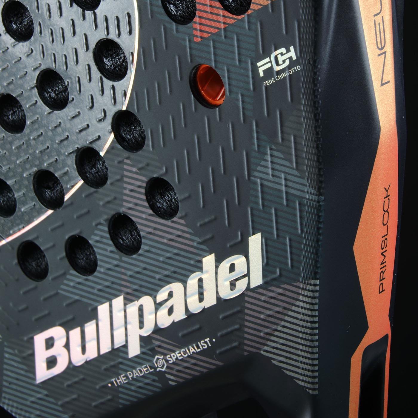 Close-up of the Bullpadel Neuron 02 Edge 2026 padel racket, featuring a textured black surface with circular holes, geometric patterns, Bullpadel logos, advanced PrismLock technology, and orange as well as metallic accents on the edge.