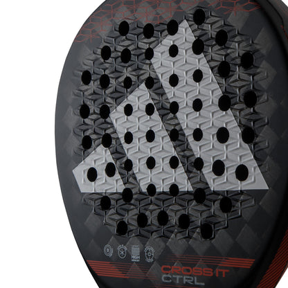 Close-up of the adidas Cross It CTRL Padel Racket, featuring a geometric pattern, ventilation holes, "CROSS IT CTRL" at the base, and a bold white and gray triangular adidas logo.