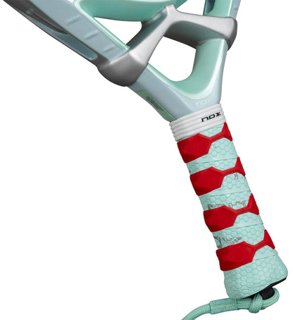 Close-up of the NOX Luxury Ventus 12K Hybrid Lite 2026 padel racket’s handle with a light blue grip, red accents, honeycomb texture, branded tag near the handle, and durable 12K carbon fibre construction.