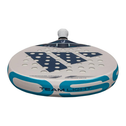 A close-up of the adidas Cross It Team Light 3.4 Padel Racket features circular holes, a prominent "W" logo at the center, "TEAM LIGHT" at the base, and a white grip on the handle.