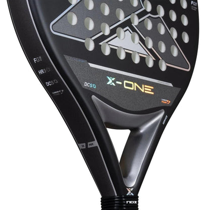 Close-up of the NOX X-One Advance Series Padel Racket in black, featuring a triangular hole near the handle, silver accents, circular perforations, and visible HR3 rubber core details. Brand: NOX.